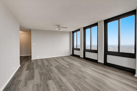 an empty living room with a ceiling fan and a view of the city
